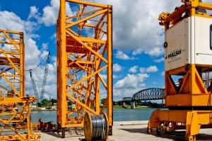 Mast section and power cable sitting on barge with other sections and cab.